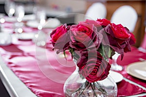 Closeup shot of a vase of red roses as decoration on a wedding table