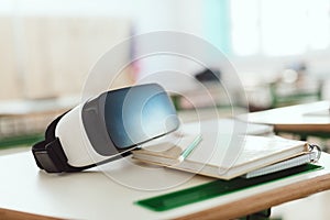 Closeup shot of virtual reality headset on table with textbook and pencil