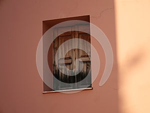 Closeup shot of a weathered wooden window in a pink wall