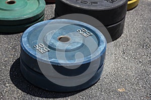 Closeup shot of weight plates differentiated by weights and colors, lying on the ground