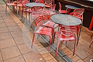 Closeup shot of wet red plastic outside cafe chairs and metal tables after rain