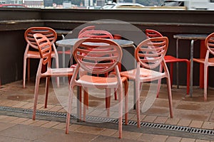 Closeup shot of wet red plastic outside cafe chairs and metal tables after rain