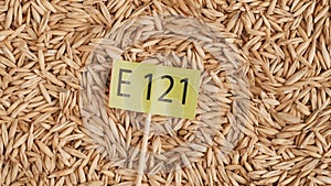 Closeup shot of wheat grains background and paper sign with E 121 written on it.