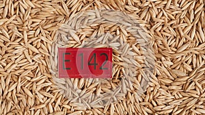 Closeup shot of wheat grains background and red paper with E 142 written on it.