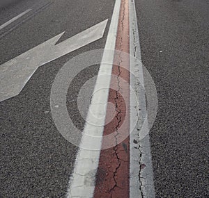 Closeup shot of a white arrow on the asphalt of a road traffic signal and the red line