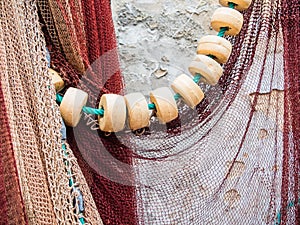 Closeup shot of white beads on a green rope and hanging white red mesh of a fishing net