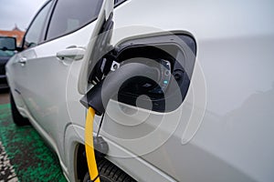 A closeup shot of a white car refueling gasoline by auto dispenser nozzle at a petrol station