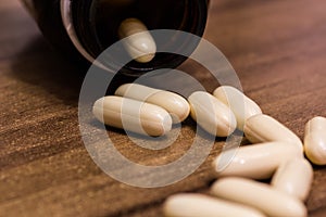 Closeup shot of white medicine capsules on a wooden surface