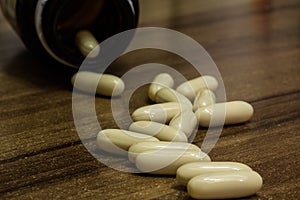 Closeup shot of white medicine capsules on a wooden surface