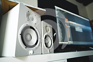 closeup shot of the white speakers, MIDI sequencer in the background, recording studio