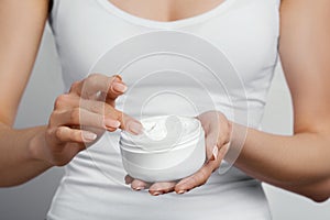 Closeup shot of woman hands holding cream and applying moisturizing hand cream. Beautiful female hands with cream.