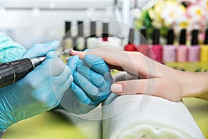 Closeup shot of a woman in a nail salon receiving a manicure by a beautician with nail file. Woman getting nail manicure