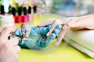 Closeup shot of a woman in a nail salon receiving a manicure by a beautician with nail file. Woman getting nail manicure