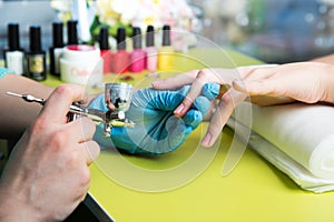 Closeup shot of a woman in a nail salon receiving a manicure by a beautician with nail file. Woman getting nail manicure