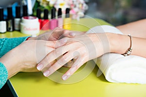 Closeup shot of a woman in a nail salon receiving a manicure by a beautician with nail file. Woman getting nail manicure