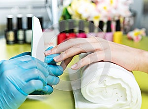 Closeup shot of a woman in a nail salon receiving a manicure by a beautician with nail file. Woman getting nail manicure