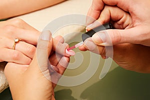 Closeup shot of a woman in a nail salon receiving a manicure by a beautician with nail file. Woman getting nail manicure