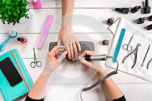 Closeup shot of a woman in a nail salon receiving a manicure by a beautician with nail file. Woman getting nail manicure