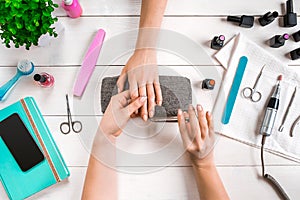 Closeup shot of a woman in a nail salon receiving a manicure by a beautician with nail file. Woman getting nail manicure