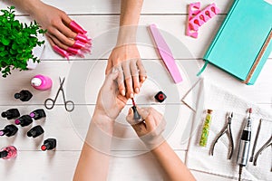 Closeup shot of a woman in a nail salon receiving a manicure by a beautician with nail file. Woman getting nail manicure