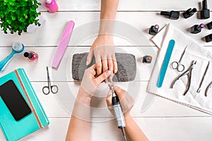 Closeup shot of a woman in a nail salon receiving a manicure by a beautician with nail file. Woman getting nail manicure