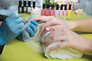 Closeup shot of a woman in a nail salon receiving a manicure by a beautician with nail file. Woman getting nail manicure. Beautici