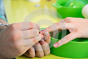 Closeup shot of a woman in a nail salon receiving a manicure by a beautician with nail file. Woman getting nail manicure. Beautici