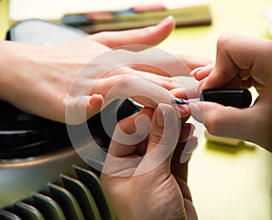 Closeup shot of a woman in a nail salon receiving a manicure by a beautician with nail file. Woman getting nail manicure. Beautici