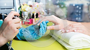 Closeup shot of a woman in a nail salon receiving a manicure by a beautician with nail file. Woman getting nail manicure. Beautici