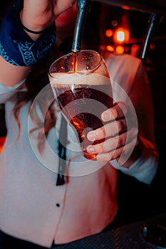 Closeup shot of a woman wearing a white shirt pouring craft beer in a tall glass