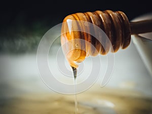 Closeup shot of a wood dipper of honey and honey leaking from it