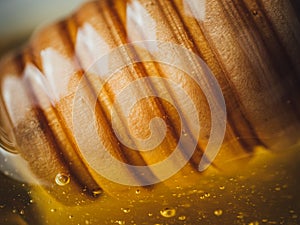 Closeup shot of a wood dipper of honey with studio lights reflecting on it