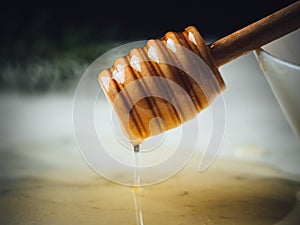 Closeup shot of a wood dipper of honey in a white plate and honey leaking from it