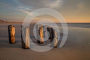 Closeup shot of wooden beach posts on a coast under the clouded sky in the evening