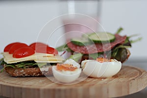 Closeup shot of a wooden board with a breakfast sandwich and soft boiled eggs