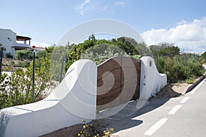 Closeup shot of wooden gates in the middle of two white walls on the garden background