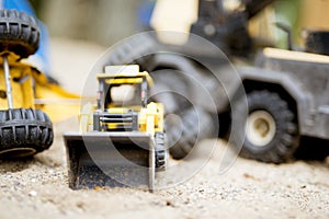 Closeup shot of a yellow bulldozer on a sandy surface with a blurred background