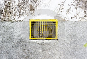 Closeup shot of a yellow rusty metal window grill on an old wall with cracks