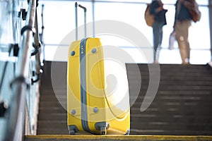 closeup shot of yellow wheeled bag and couple of tourists at subway