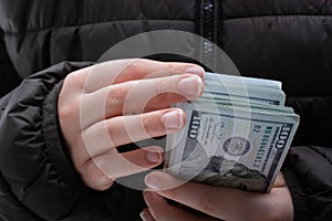 Closeup shot of a young female counting a pack of dollars