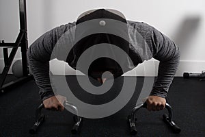 Closeup shot of a young fit male working out on push-up grips