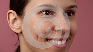 Closeup shot of young girl face with natural skin, no makeup, smiling with teeth. Looking away from camera.