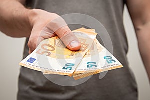 Closeup shot of a young man holding 150 euros in his hand