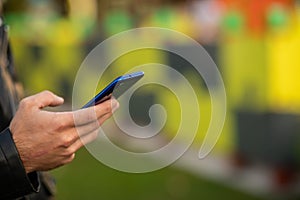 Closeup shot of an young modern man holding mobile phone in hand, blurred background