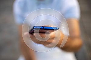 Closeup shot of an young modern man holding mobile phone in hand, blurred background