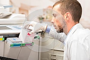 Closeup shot young technician refilling toner in