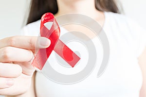 Closeup shot of a young woman holding a red ribbon - world AIDS day concept