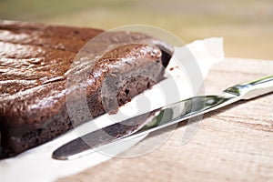 Closeup side of brownie. Knife nearly and shadow light. Dessert