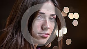 Closeup side view portrait of young pretty caucasian female model with her hair fluttering looking at camera and smiling