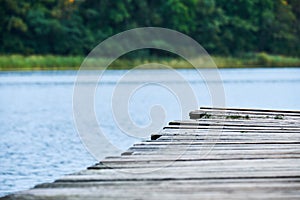 Closeup of the side of a wooden pier running diagonally across the frame with the lake and shore visible in the background